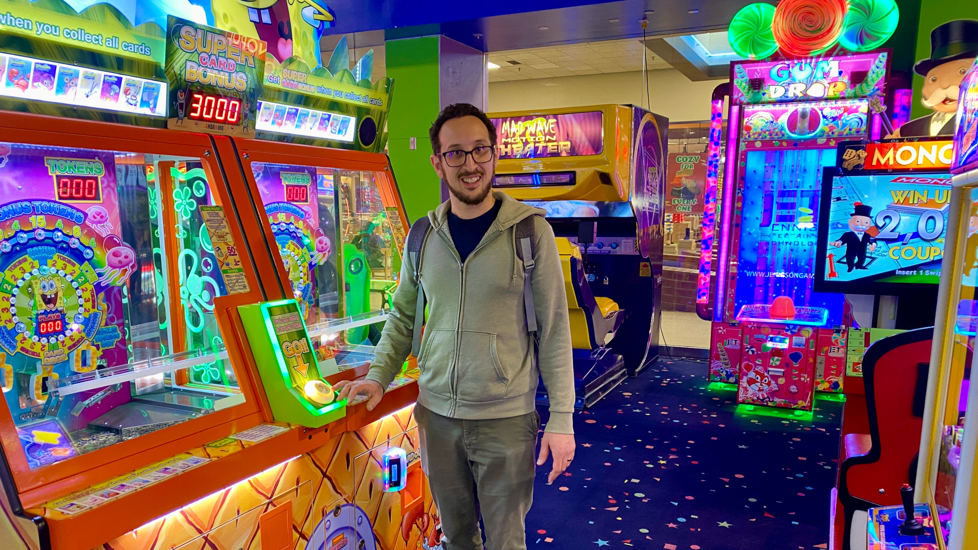 Colorful arcade games surrounding a man standing next to a ticket game.